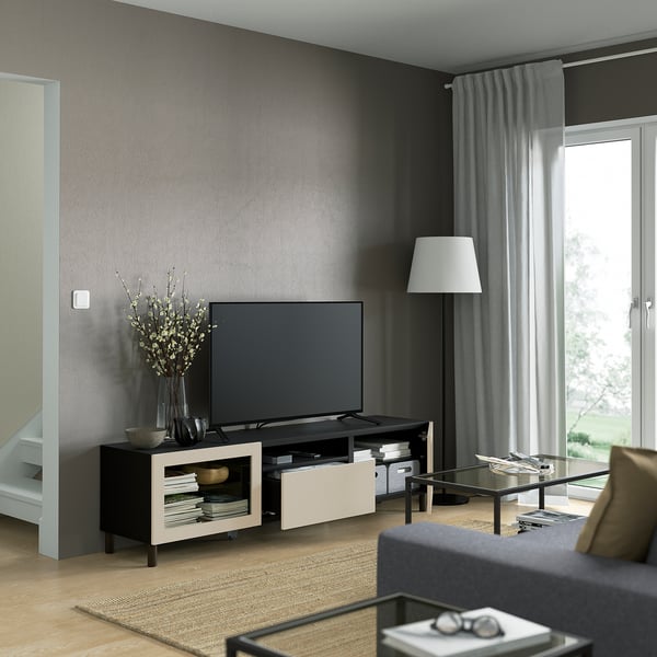 Modern living room with gray walls, flat-screen tv, and glass coffee table. Remote-controlled drawers and cable management visible.