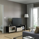 Modern living room with gray walls, flat-screen tv, and glass coffee table. Remote-controlled drawers and cable management visible.
