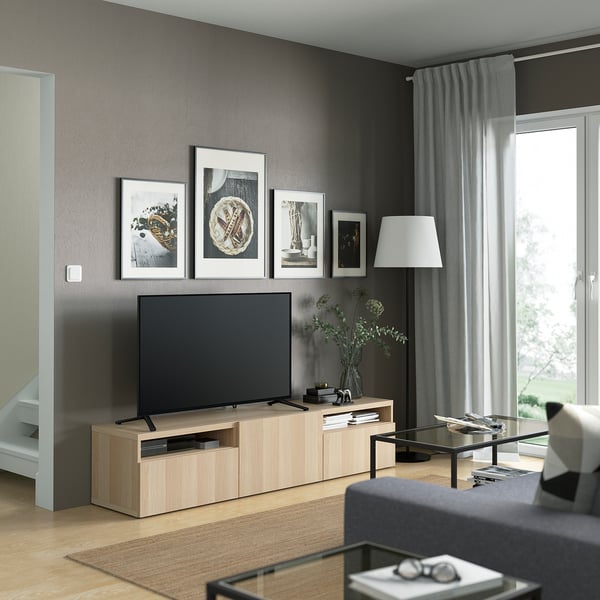 Modern living room: BESTÅ tv unit, art, grey sofa, glass table, lamp, large window.