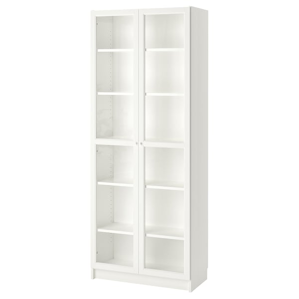 A tall, white BILLY bookcase with glass doors. It has multiple shelves, a modern, minimalist design, and is made of particleboard and glass.