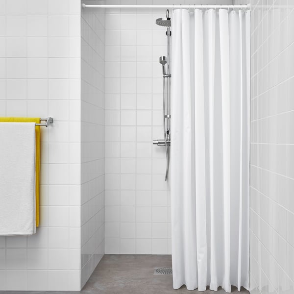 Simple, modern bathroom with white tiles. Shower peva curtain for water repellent ease. Yellow towel rail adds color.