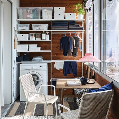 Displays a white BOAXEL wall-mounted storage system featuring multiple shelves and a drying rack, ideal for organizing laundry items.