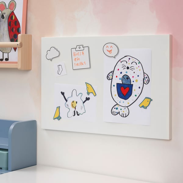 Colorful magnet board on pink wall with drawings, notes, & sheep figurine.