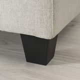 A modern sofa with a sleek, dark wooden leg and light gray cushioned seat, showcasing high-quality design and comfort.