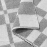 Checkered bedspread folded, showing soft texture and sturdy stitching.
