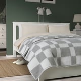 Gray checkered BORSTTÅG bedspread on large bed, against green wall.