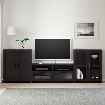 Modern black tv setup: wide stand, flat screen, white lamp, art.