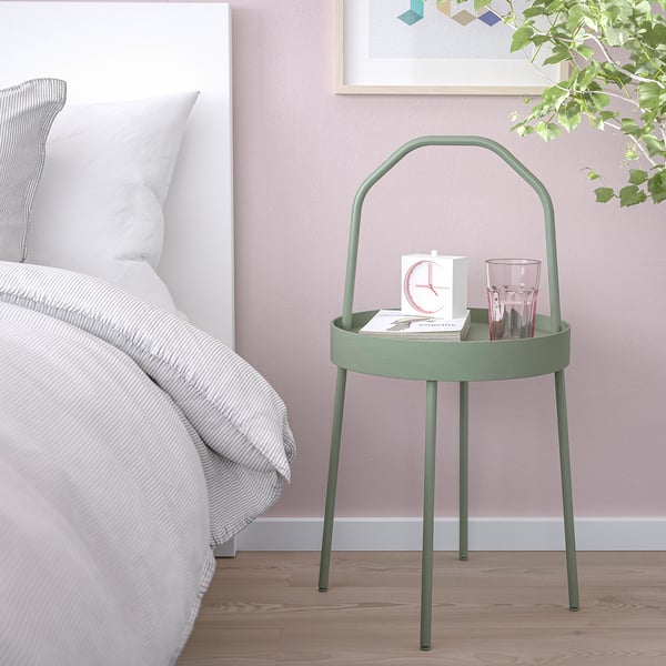 Green BURVIK side table with handle, clock, and glasses beside bed.