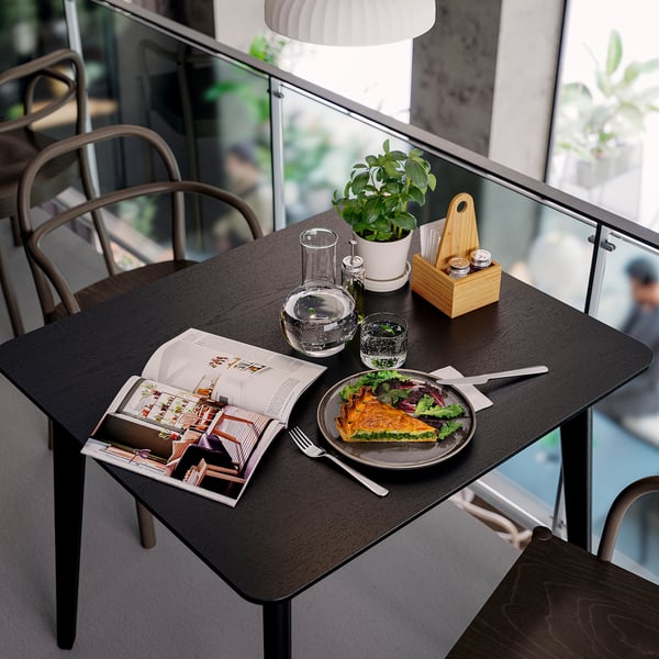 Modern dining setup with CHOKLADHAJ black organiser, holding plants, glasses, and cutlery beside a plate of quiche.