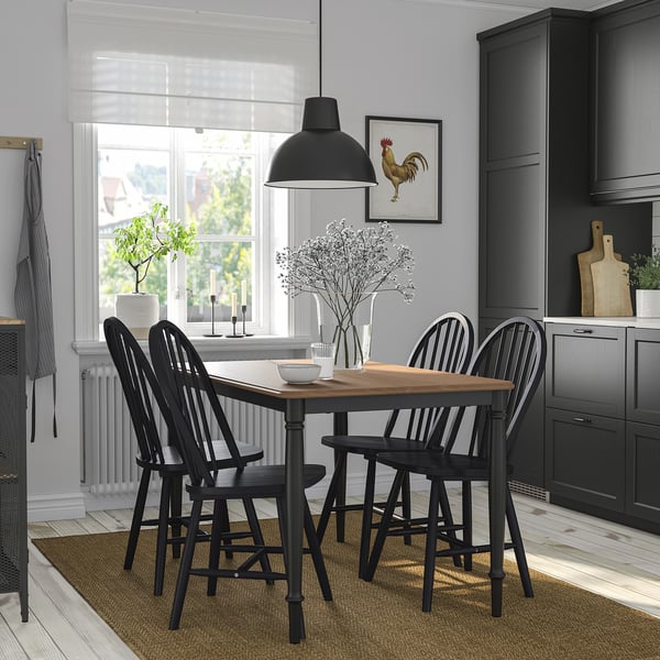 Modern dining set with black legs, wood top, seats four, large light, small window, gray cabinets.