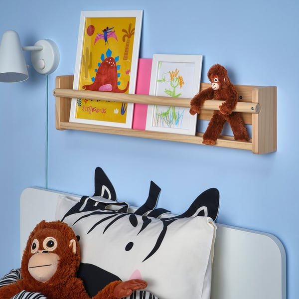 Kids room with DJUNGELSKOG monkey toy, zebra pillow, and artwork on shelf.