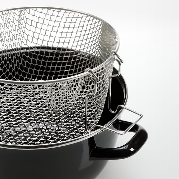 Stacked stainless steel frying baskets with black handles on a white surface.