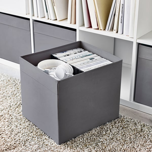 Gray fabric storage box on shelf, holding pencil cases and stationery, part of kallax system.