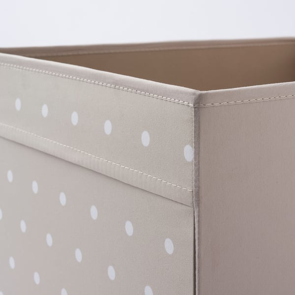 Close-up of stylish fabric storage box. Light grey with white dots, neatly stitched for durability.