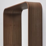 Dark wooden-framed mirror with curved top, leaning against a wall. High-quality veneer finish, reflecting light and creating a warm atmosphere.