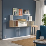 Modern blue room with wall-mounted white & wood record storage, chair, stool, art.