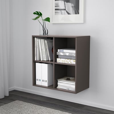A wall-mounted EKET storage cabinet. It holds books, games, and a vase on its shelves. The cabinet is efficient for space-saving and organization.