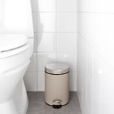 Beige bathroom trash can with foot pedal and handle, next to toilet.