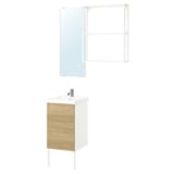 Modern bathroom setup. White cabinet with wooden door, clear glass mirror, chrome tap.