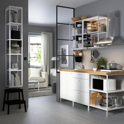 Modern kitchen with white ENHET units, wooden counter, and open shelves. Greenery and appliances complement the clean design.