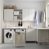 Modern laundry room with ENHET cabinets, washer, sink, hanging space, and laundry bag on wheels.