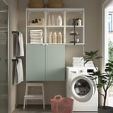 Modern laundry: white washing machine, shelves, towels, basket, cabinet, stool, plant.
