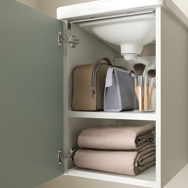 Open bathroom cabinet with towels, makeup bag, and toiletries stored inside.