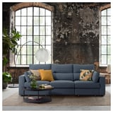 Modern living room with blue ESKILSTUNA sofa, colorful pillows, round coffee table, large arched windows, and floor lamp.