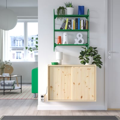 Modern wall shelf with books, decor, and plants; wooden cabinet below; nearby window and stool.