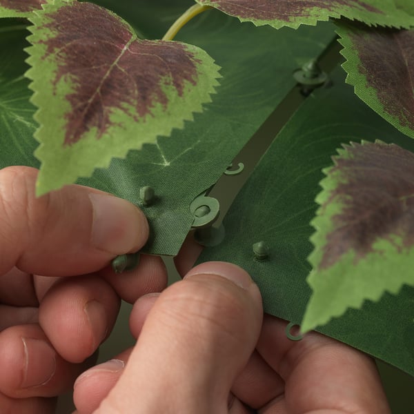 Hands assembling FEJKA plant panels with clicks.