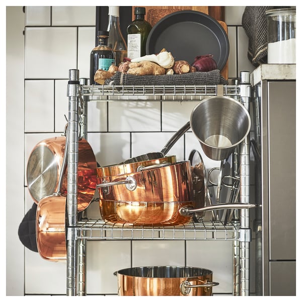 Metal kitchen shelf holding copper pots, pans, and other items.