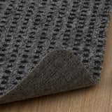 Closeup of durable grey checkered door mat laid on wooden floor, showcasing textured quality and sturdy backing.