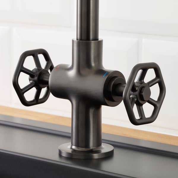 Modern black faucet with industrial-style handles mounted on a sleek sink, showcasing robust design and high-quality finish.