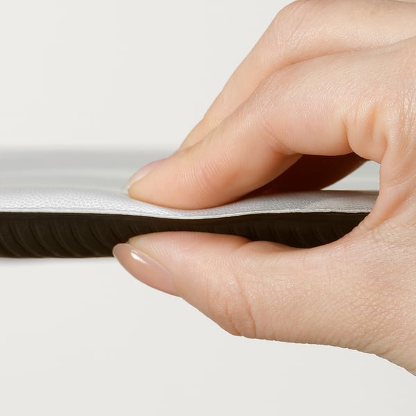 Hand firmly grips a durable, foam-filled kitchen mat, showcasing its flexibility and sturdy design, ideal for long periods of standing.