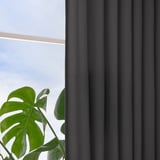 Dark grey curtains hang by window, offering privacy and light control. Large green leafy plant sits nearby.
