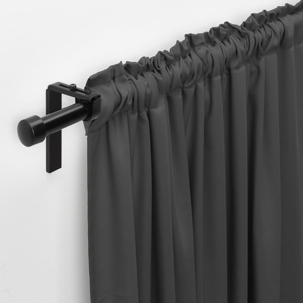 Black curtain rod holding dark grey curtains, with gathered top and wall-mounted bracket.