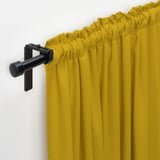 Bright yellow curtains hang from black rod, offering light control and privacy.