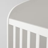 Image shows a high-quality, white, modern cot. Sleek curves, sturdy slats, and a spacious storage drawer. Perfect for a babys room.