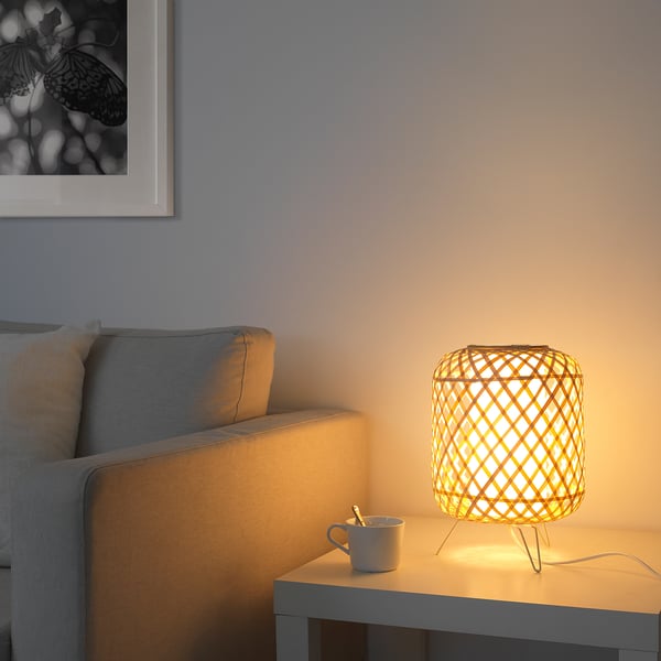 Living room with grey sofa, lit wicker lamp beside cup on table.