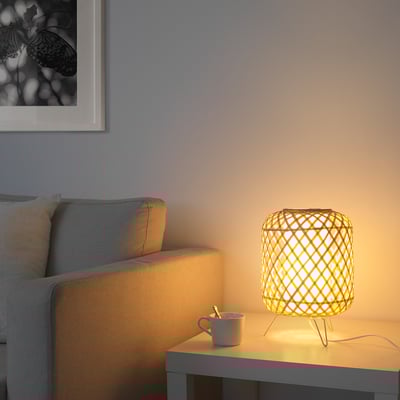 Living room with grey sofa, lit wicker lamp beside cup on table.