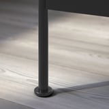Modern black metal table leg with circular base on wooden floor.
