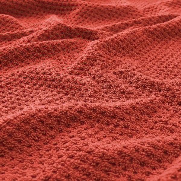 Red cotton towel close-up. Soft, textured terrycloth. Fluffy, inviting feel.