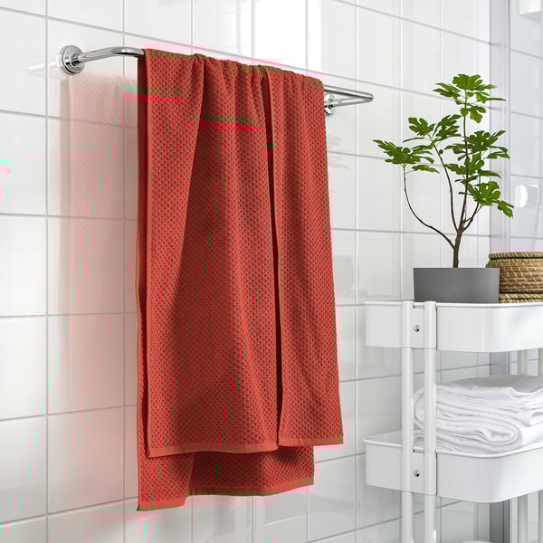 Red GULVIAL towel hangs near white shelves with towels and plant in modern bathroom.
