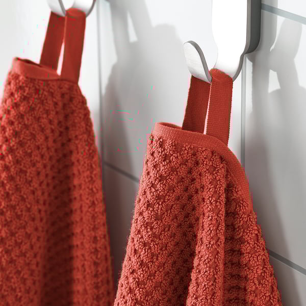 Two red towels hang on hooks, soft and fluffy, absorbent, 100% cotton.