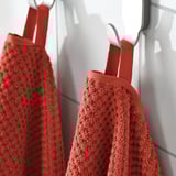 Two red towels hang on hooks, soft and fluffy, absorbent, 100% cotton.