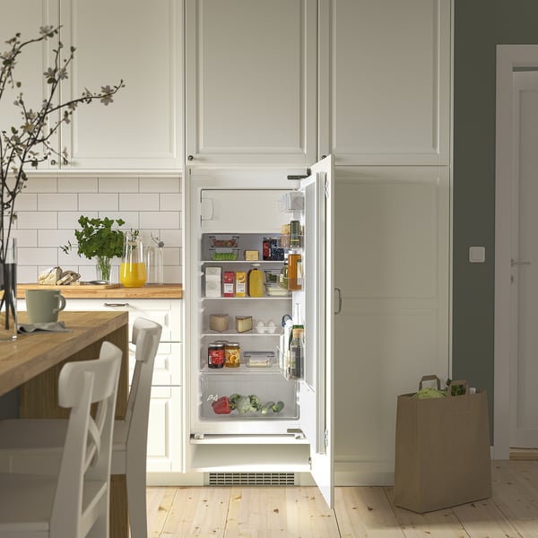 Open white fridge inside kitchen, displaying food and drinks on adjustable shelves.