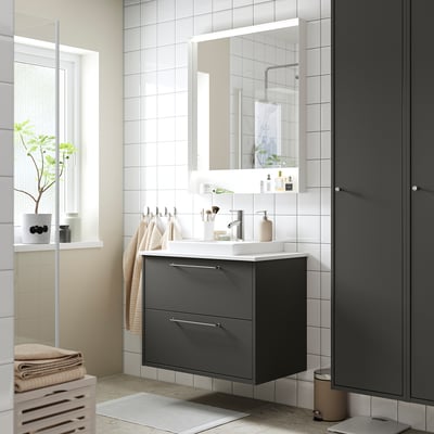 Modern grey bathroom vanity with white countertop and sink.