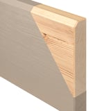 A close-up of a wooden furniture edge. The outer layer is solid pine with a clear finish, while the inner core is fiberboard.
