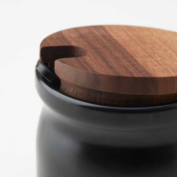 Black ceramic jar with wooden lid. High-quality, close-up view showcasing smooth surface and tight-fitting lid.