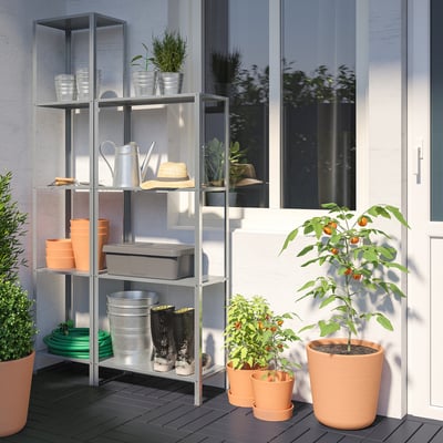 Gray HYLLIS shelf with gardening tools and plants; smaller than glass door.